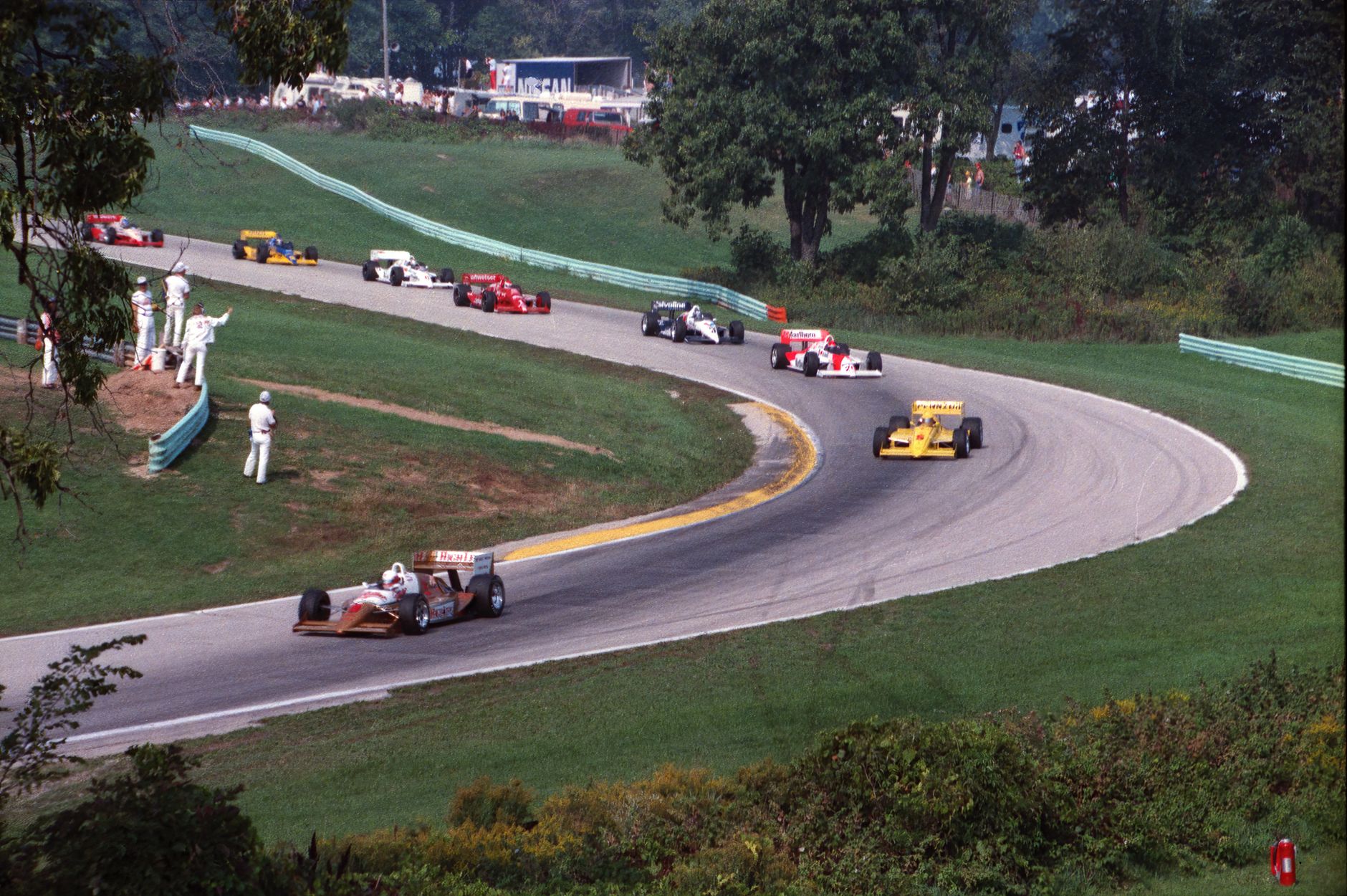 High-speed race cars on a curving track at Elkhart Lake, capturing motorsport excitement.