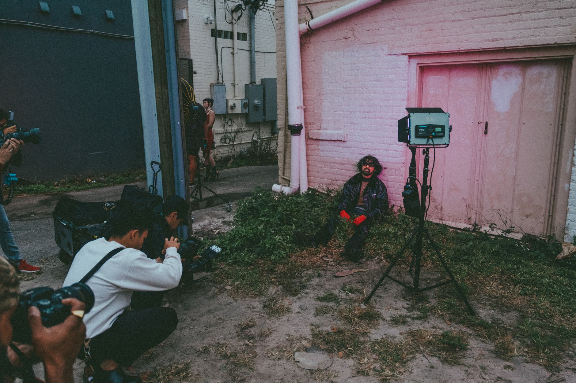 Outdoor photoshoot capturing street style modeling with photographers and lighting equipment.