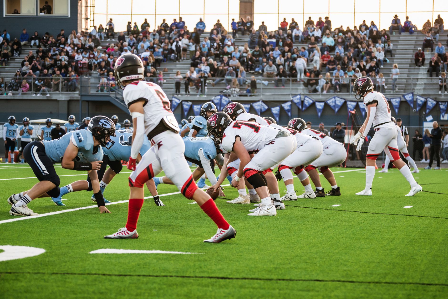Players in action during a competitive high school football game at an outdoor stadium.