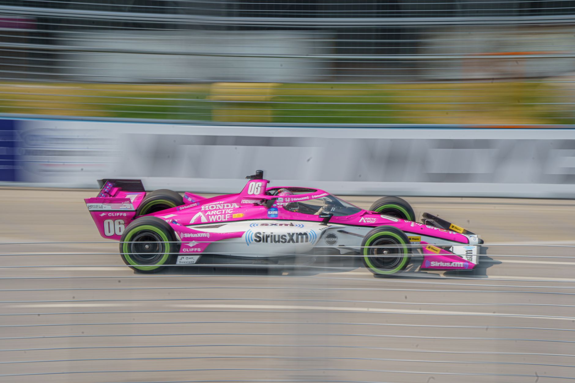 Action shot of a pink racing car with SiriusXM branding during a race in Toronto, Canada.