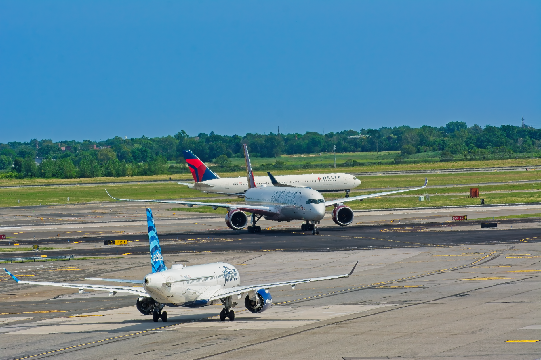 Airplanes from various airlines taxiing on a JFK airport runway in New York.