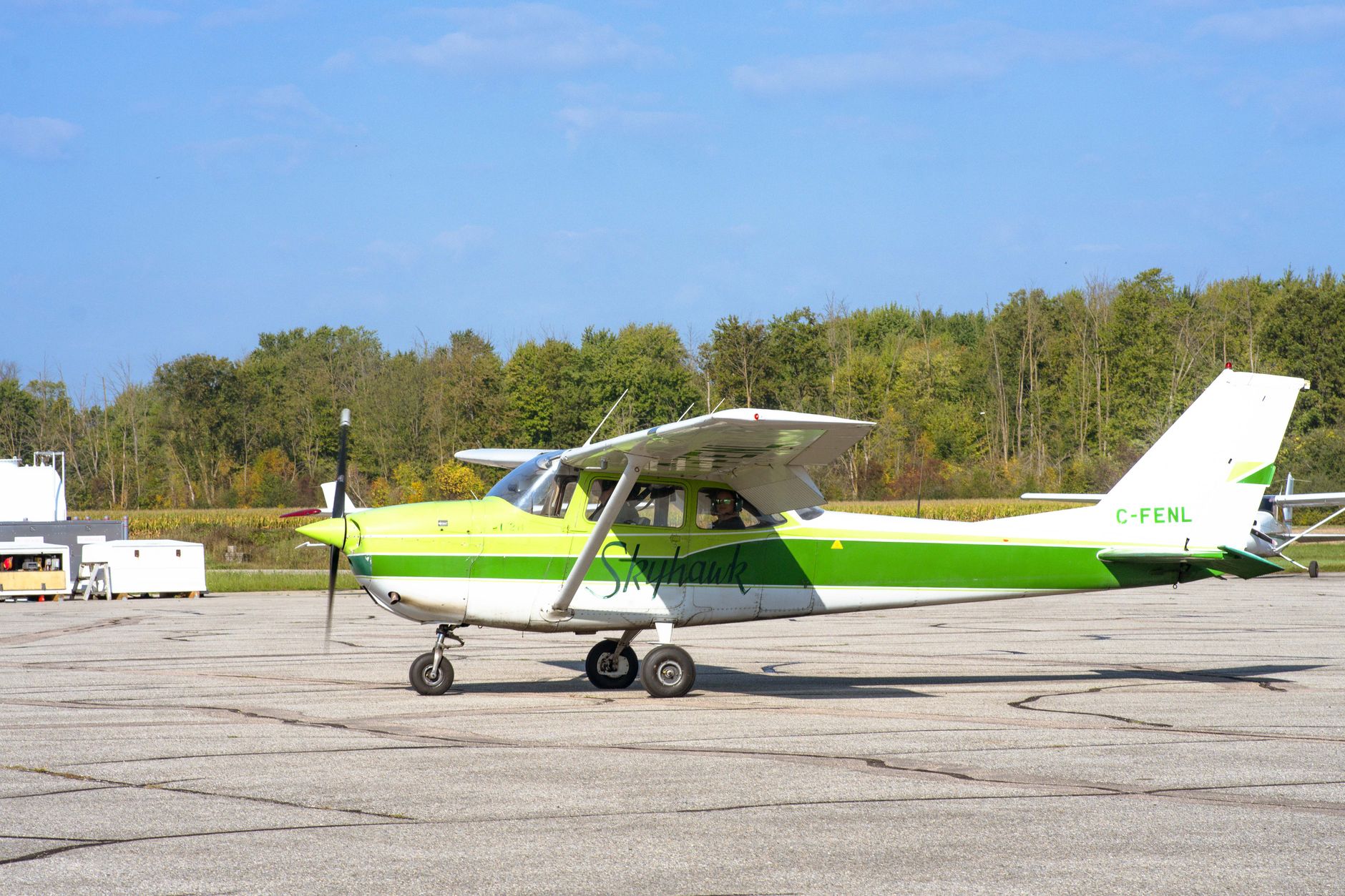 A green and white small plane parked on a tarmac at Stratford Airport, Ontario.