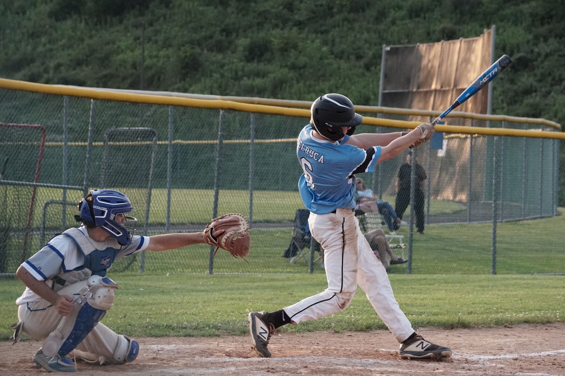Youth baseball player swings the bat during a game on a sunny day.